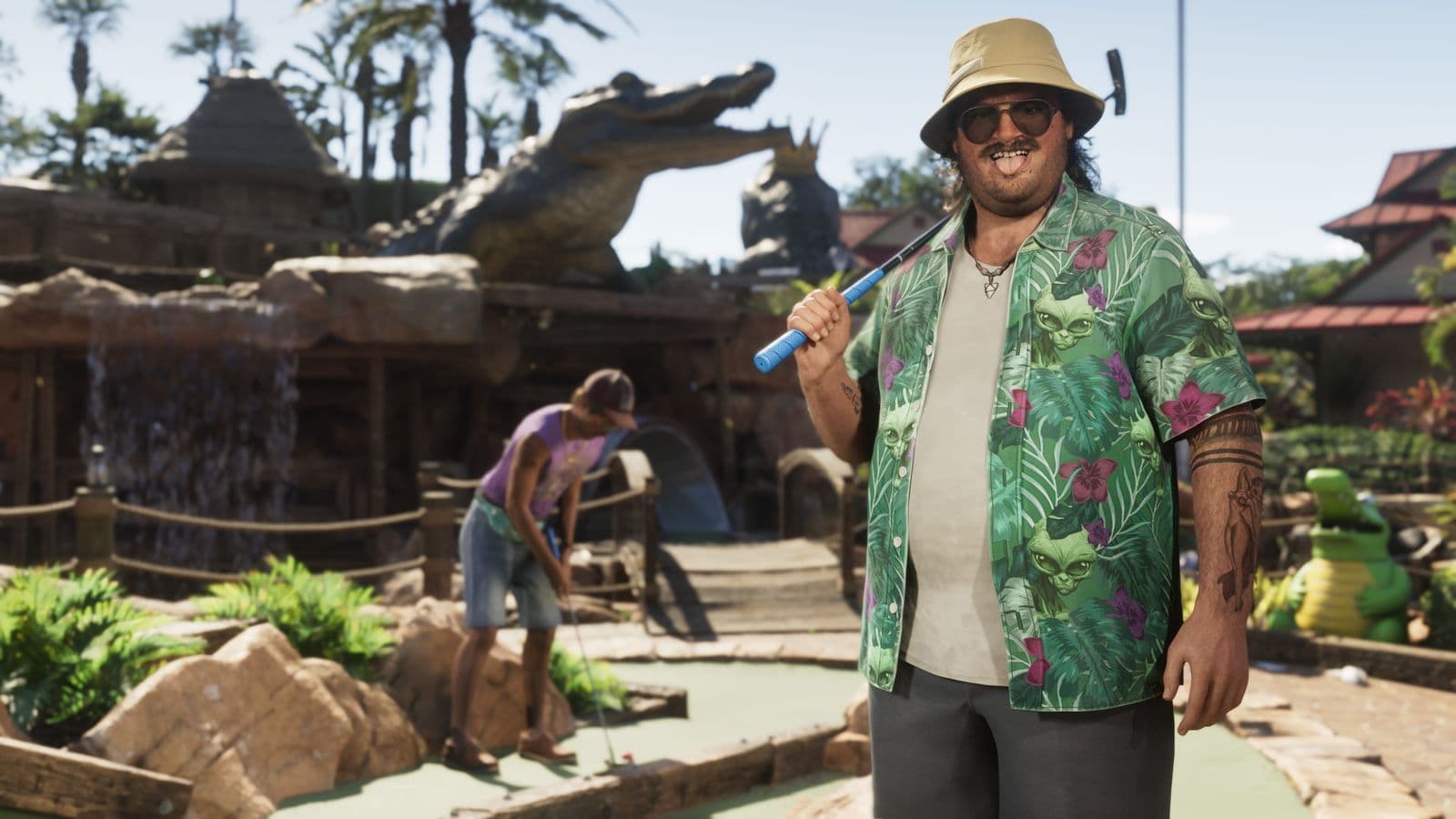 Cal Hampton in a bucket hat and Hawaiian shirt, holding a putter on a mini-golf course